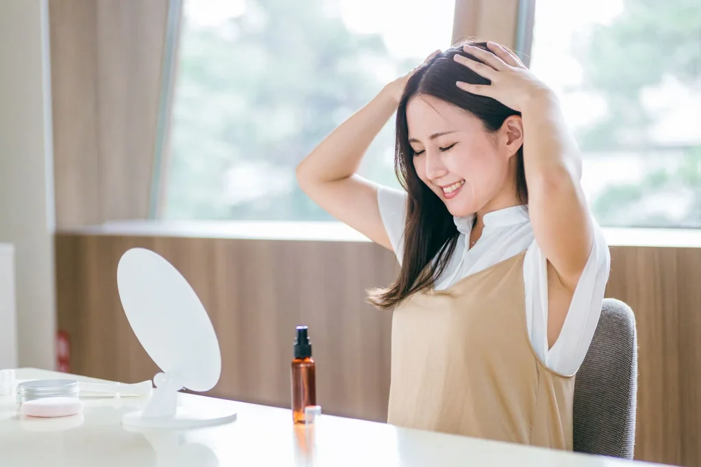 鏡を見ながら頭皮ケアをする女性