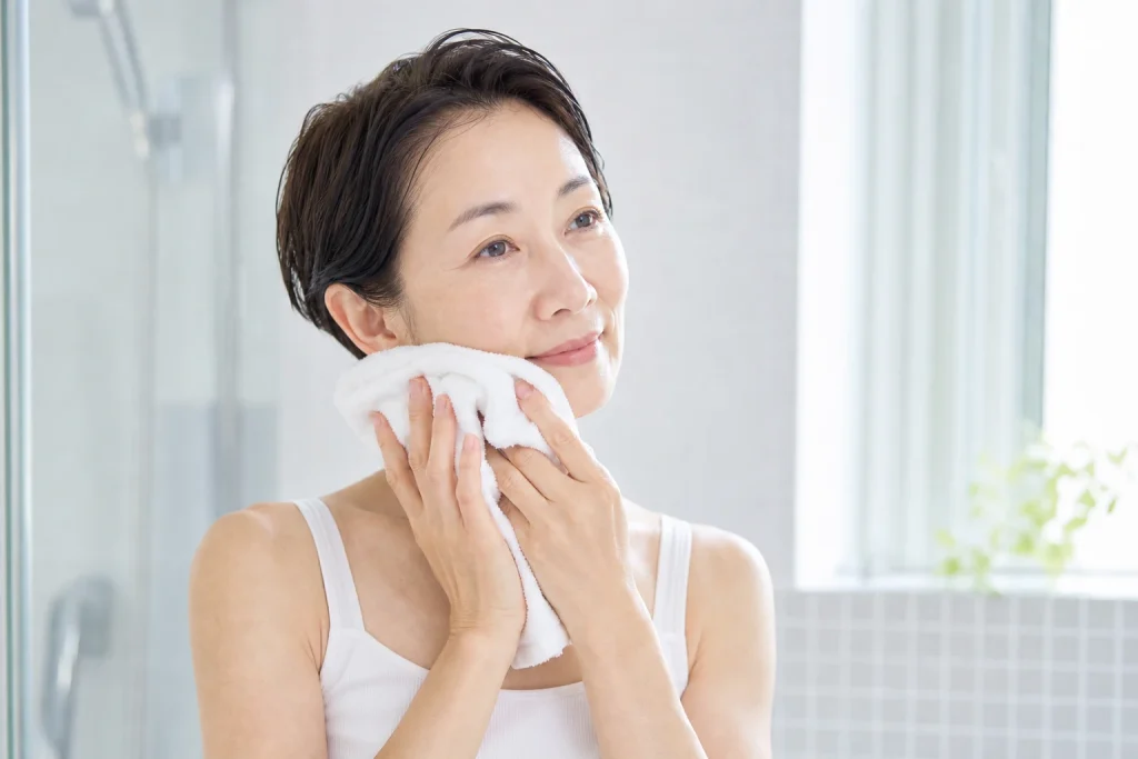タオルを顔へそっと置く50代女性