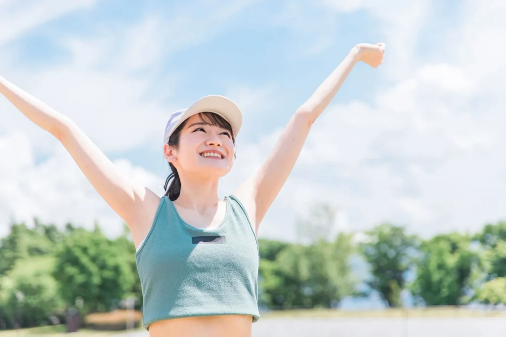 青空の下で両手を上げる運動中の女性