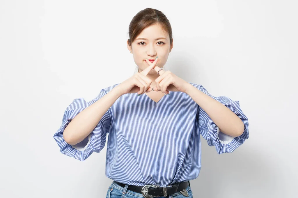 両手の人差し指でバツ印を作る女性